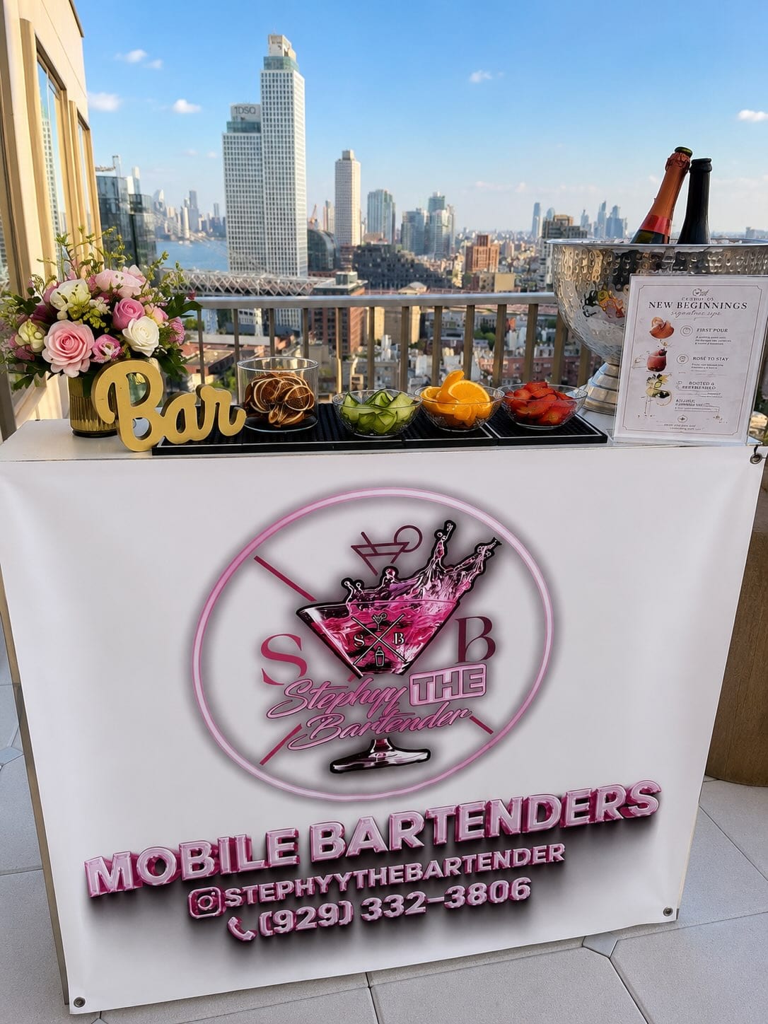 Rooftop bar setup with fresh florals, champagne on ice and a garnish tray, Manhattan skyline behind
